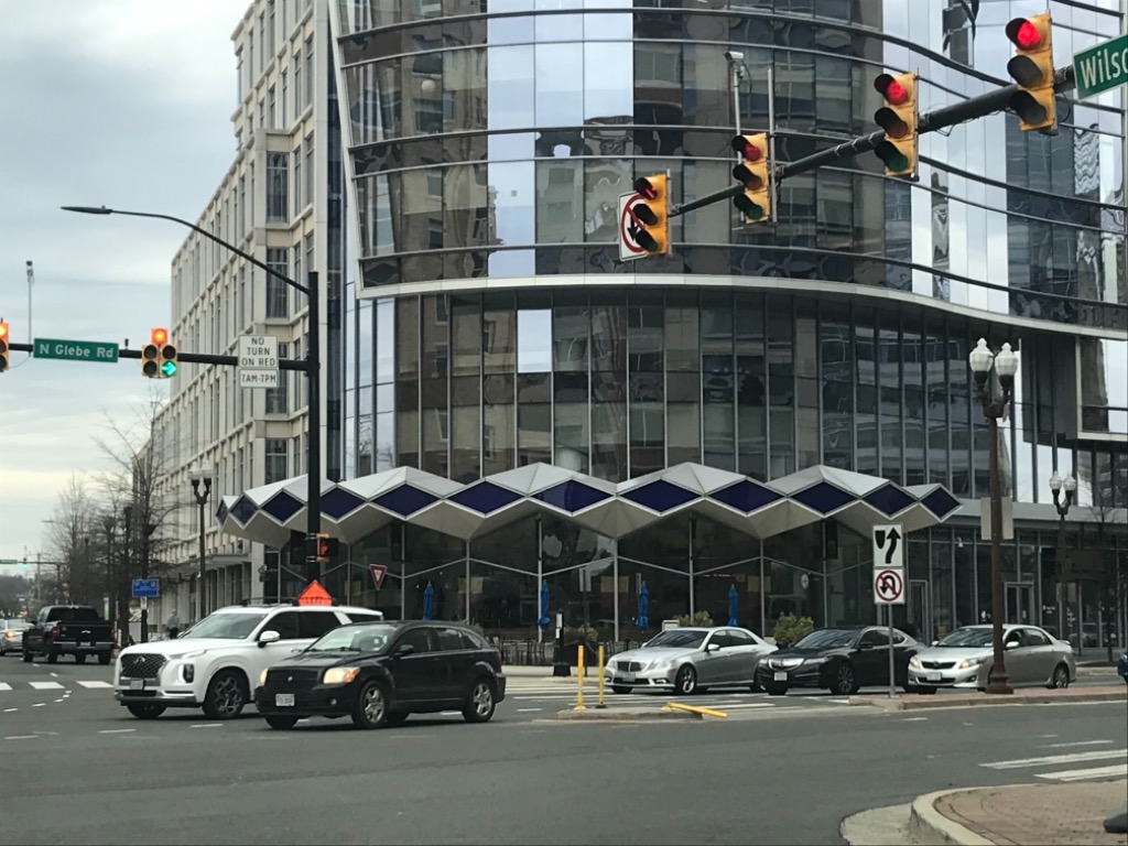At intersection of Wilson Blvd. with Glebe rd. looking at where the Bob Peck Chevrolet dealership once stood, as suggested by the vestigial line of blue diamonds across the glass front of the office building.